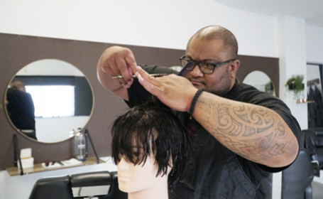 Pasifika male hair stylist cutting hair on mannequin